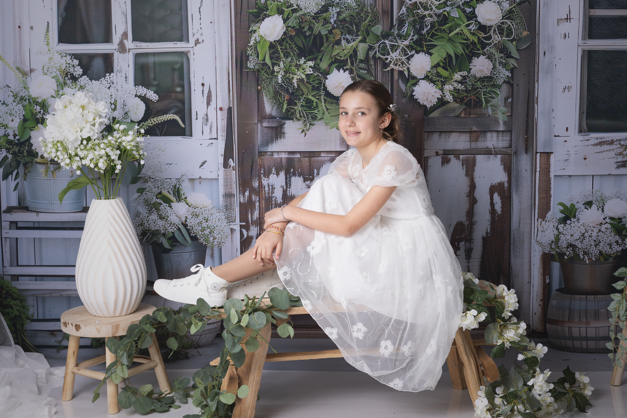 photo d'une fille pour sa communion sur un fond de studio avec des fleurs blanches