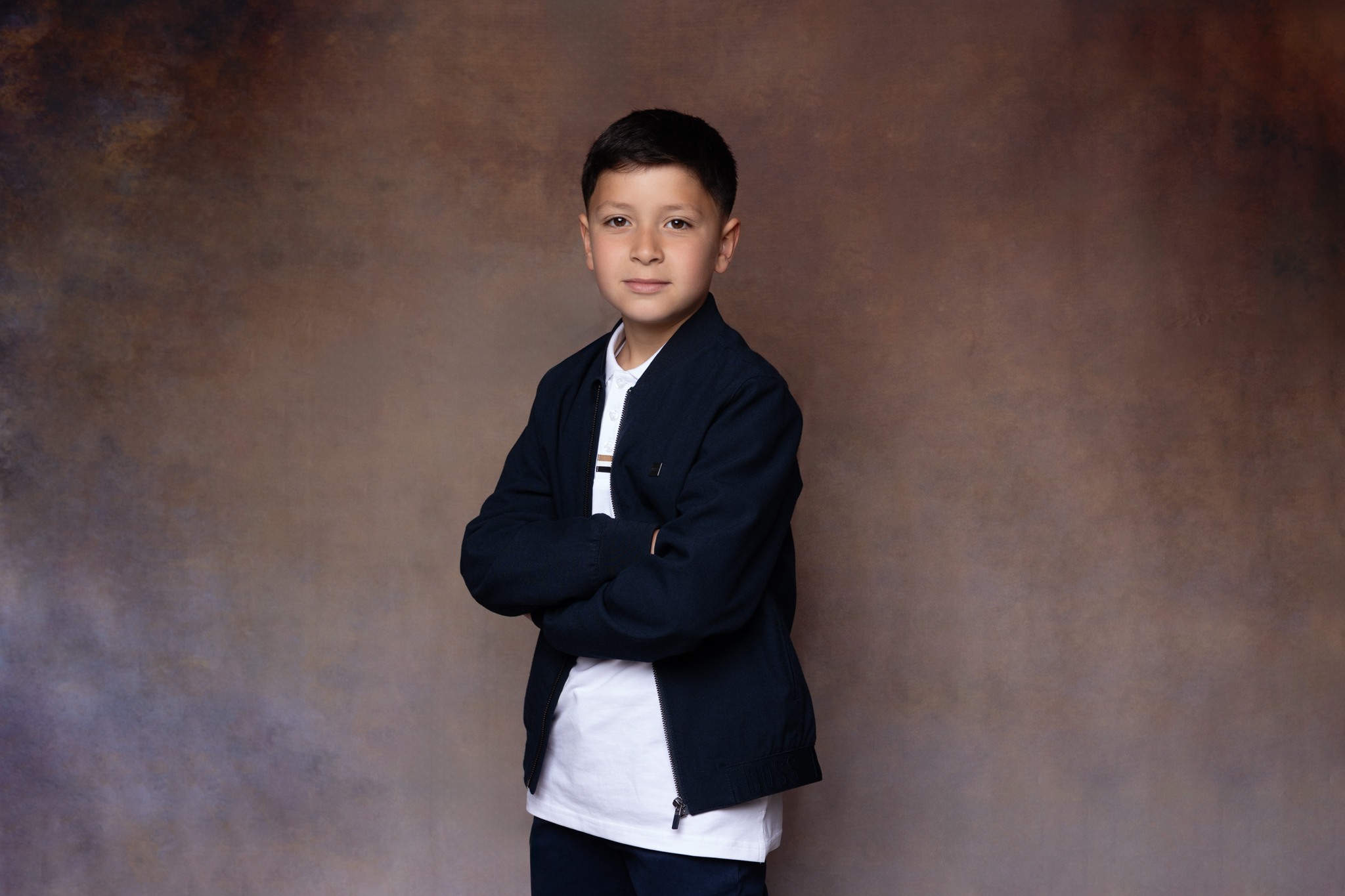 garçon en studio pour sa communion sur un fond marron 