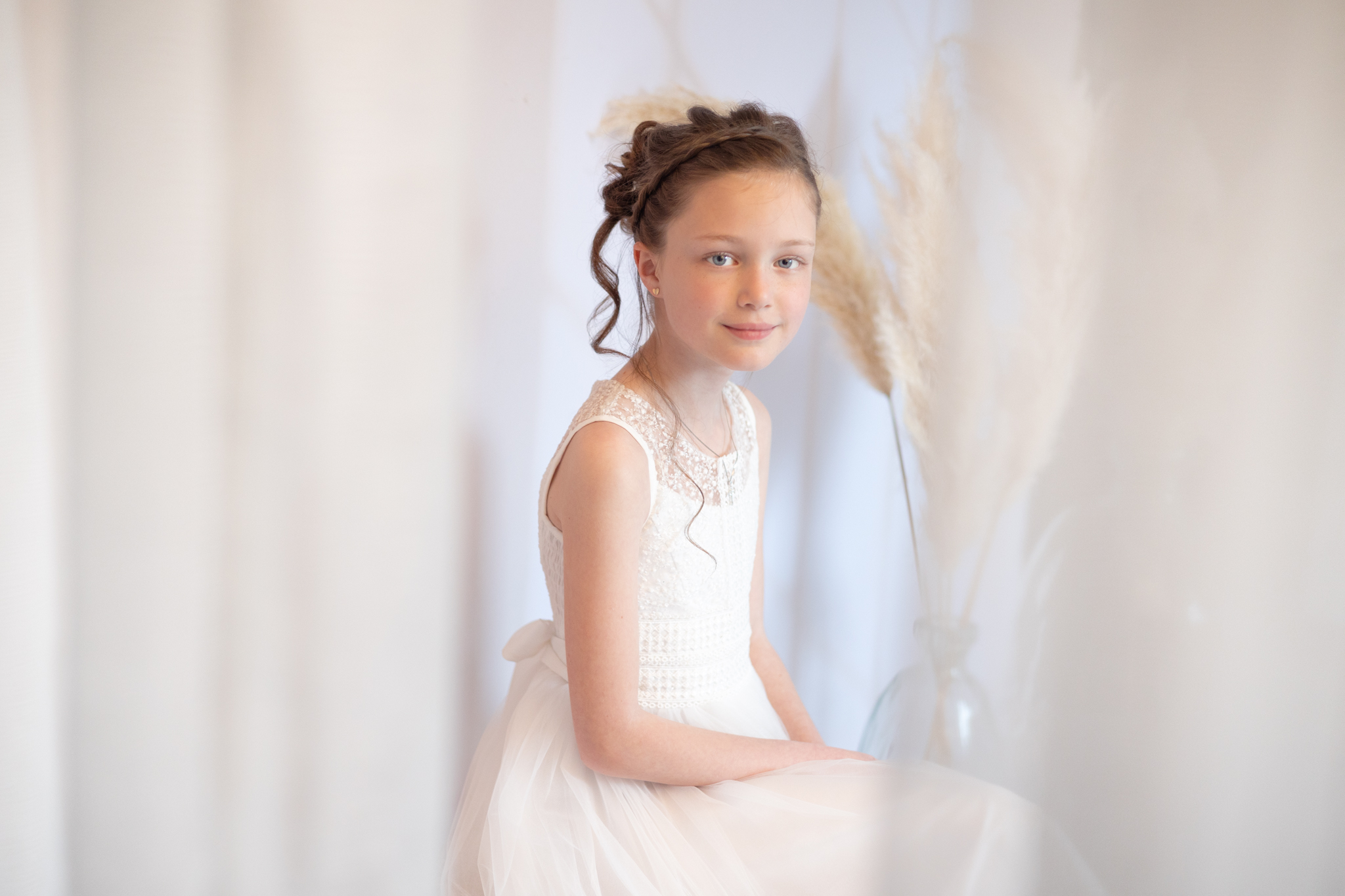 photo d'une fillette en studio pour sa communion avec un rideau blanc
