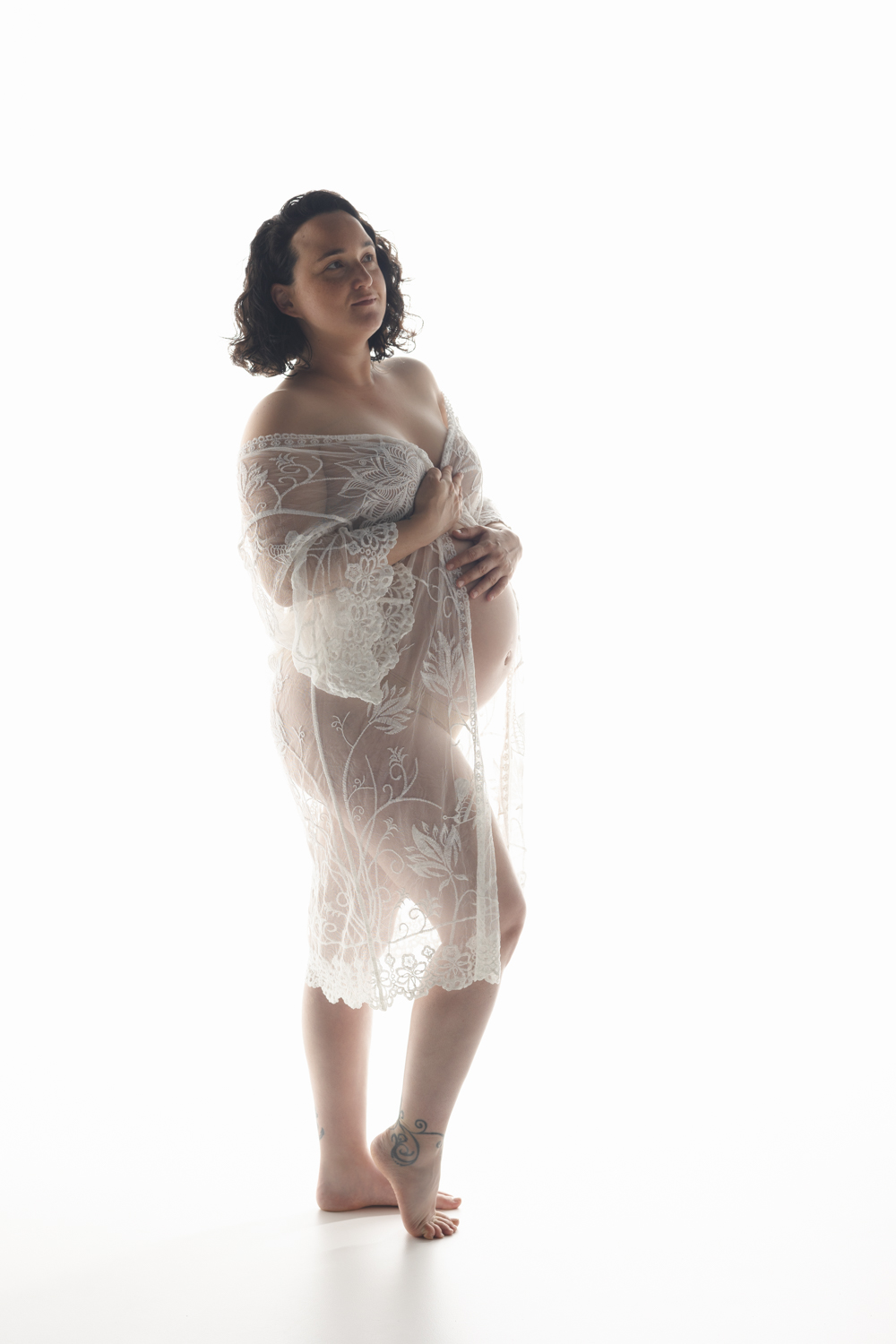 Portrait d’une femme enceinte avec déshabillé blanc en dentelle lors d’une séance grossesse en studio en Moselle.