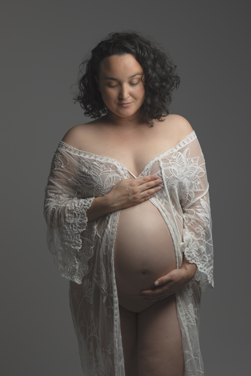 Portrait d’une femme enceinte avec déshabillé blanc en dentelle lors d’une séance grossesse en studio en Moselle.