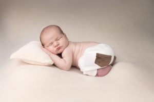 bébé en train de dormir qui pose pour une séance photo de naissance