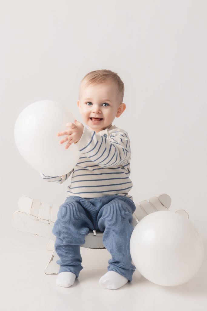 photo d'un enfant en studio avec des ballon assis sur un petit banc