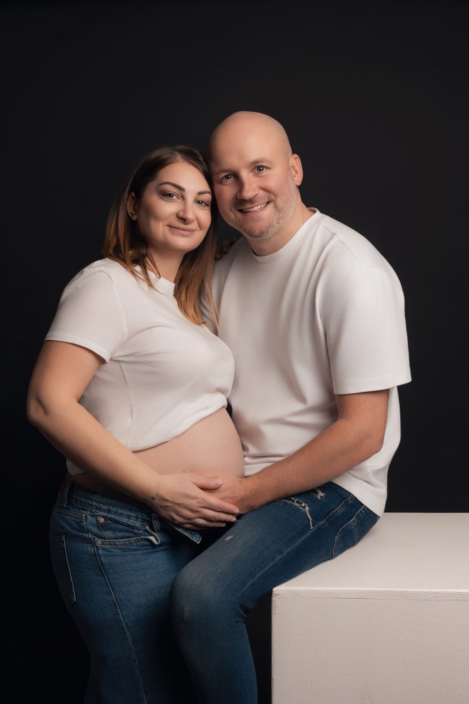 couple en séance photo grossesse habillés en jeans et haut blanc