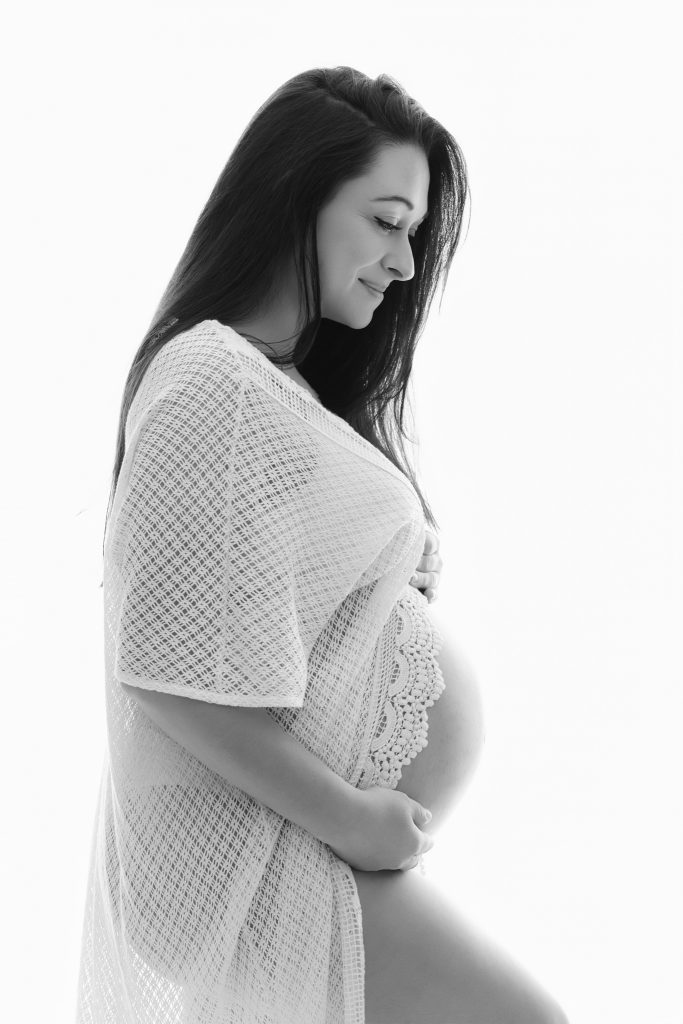femme enceinte en studio photo pour une séance en noir et blanc