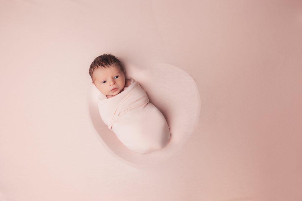 bébé à la naissance pour un shooting naissance dans un contenant en coeur 