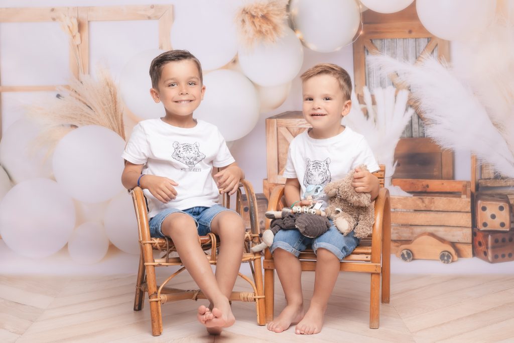 deux frères en shooting photo en studio avec une décoration bois et ballons