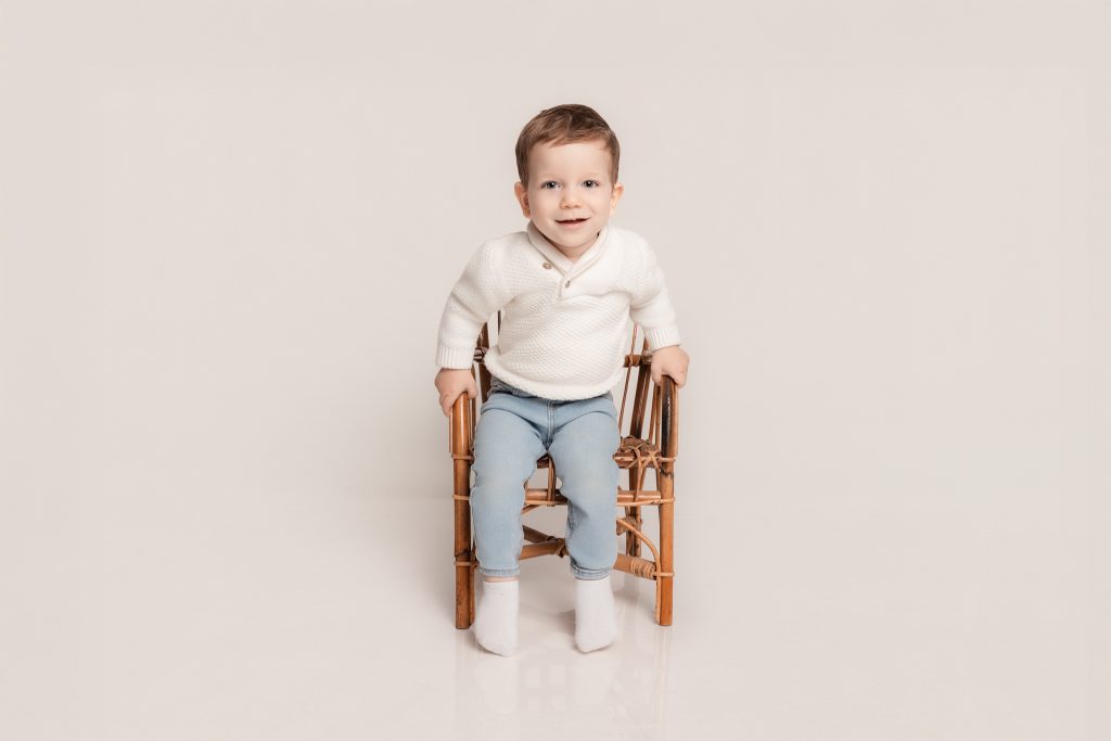 enfant en studio sur une chaise en osier