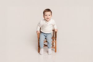 enfant en studio sur une chaise en osier