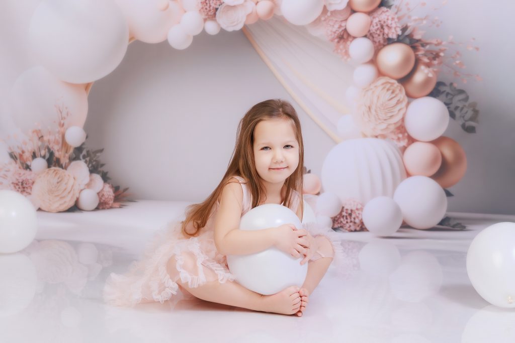 petite fille en studio photo avec une arche de ballon en arrière plan