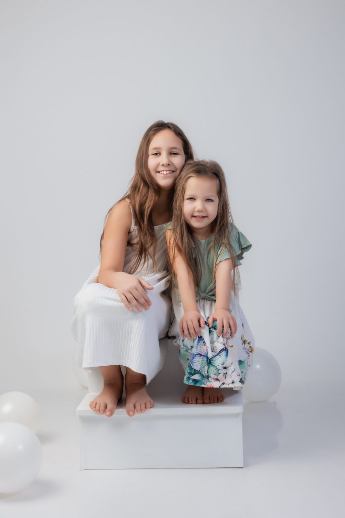 Photos de deux soeurs en studio assise sur un escalier