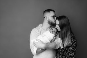 Photo en studio de parents avec leur nouveau né enveloppé