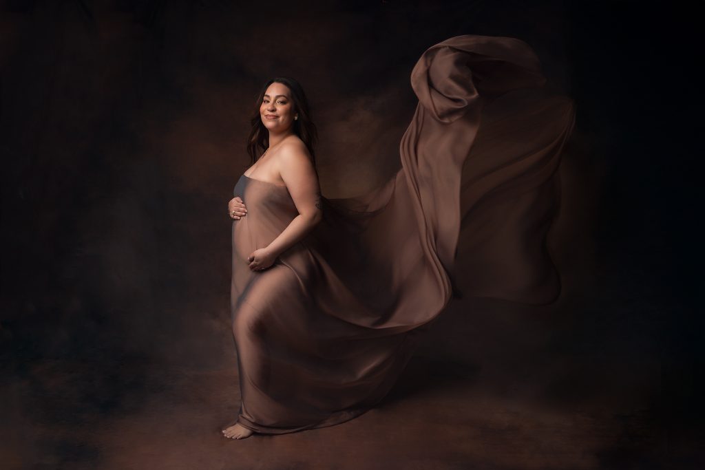 photo d'une femme enceinte en studio avec un voile qui vole 