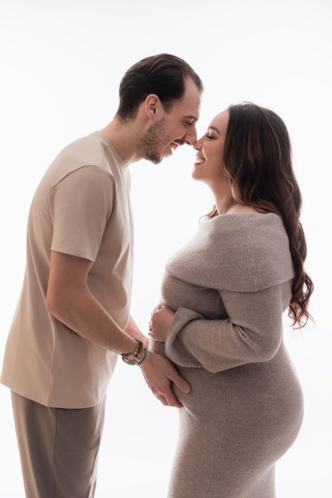 couple en studio qui rigole face à face pour une seance grossesse