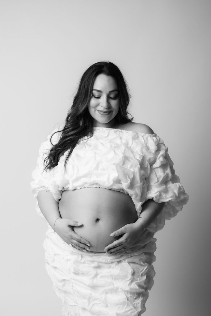 future maman en studio pour une séance photo avec une tenue blanche 