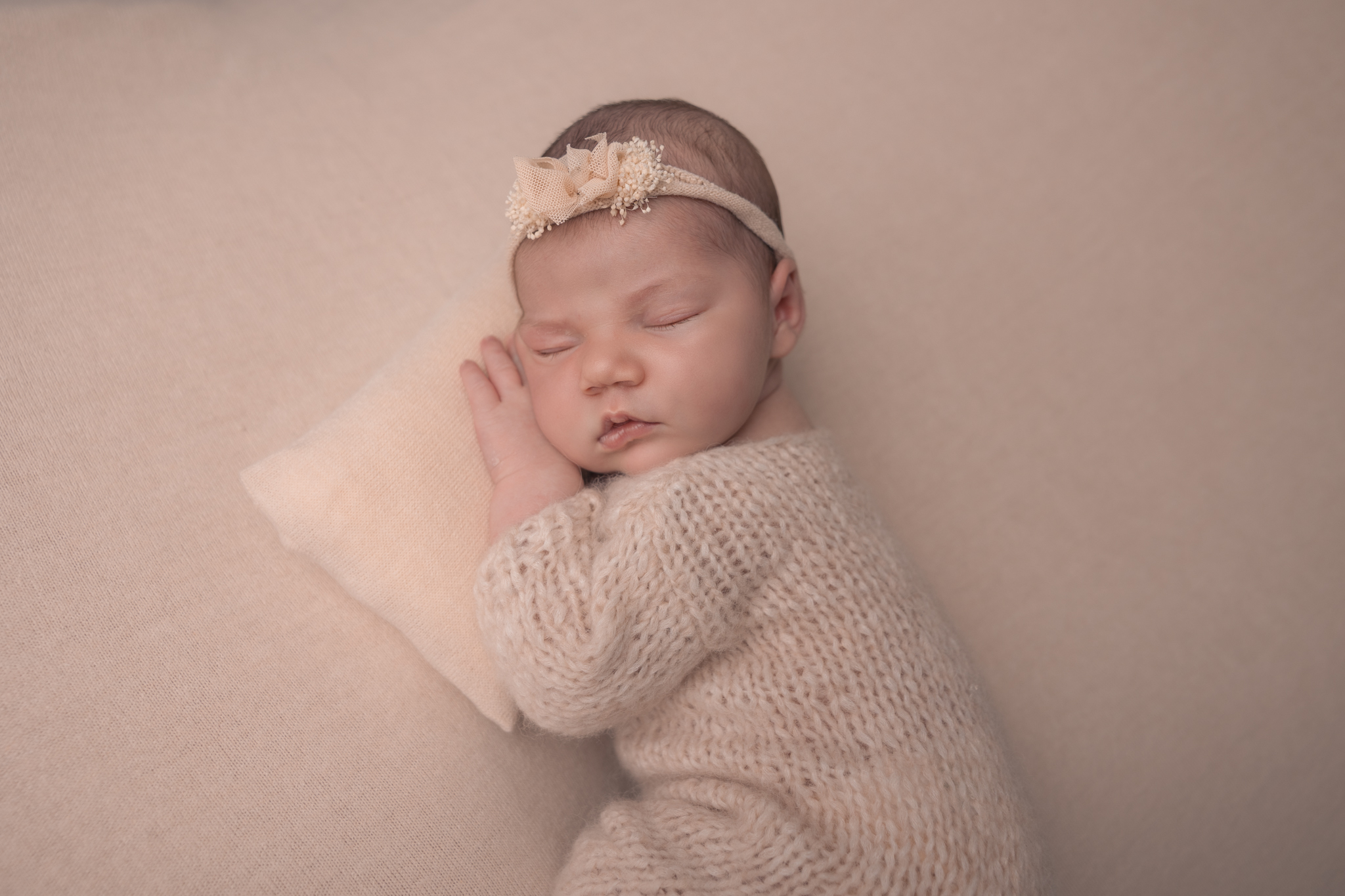photo d'un bébé en séance naissance en position bum up avec un coussin