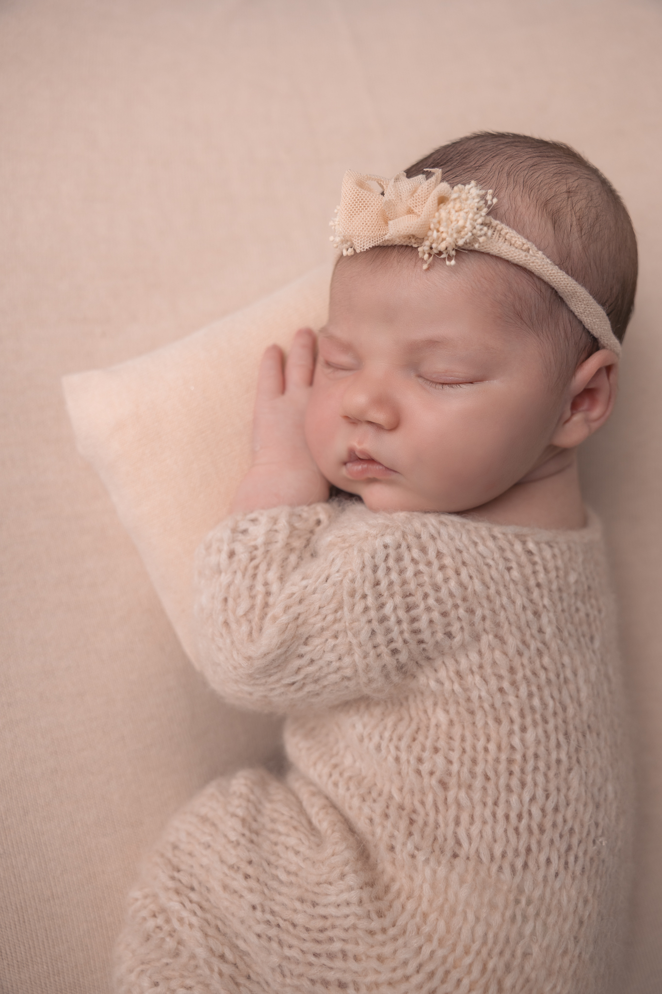 photo d'un bébé en séance naissance en position bum up avec un coussin
